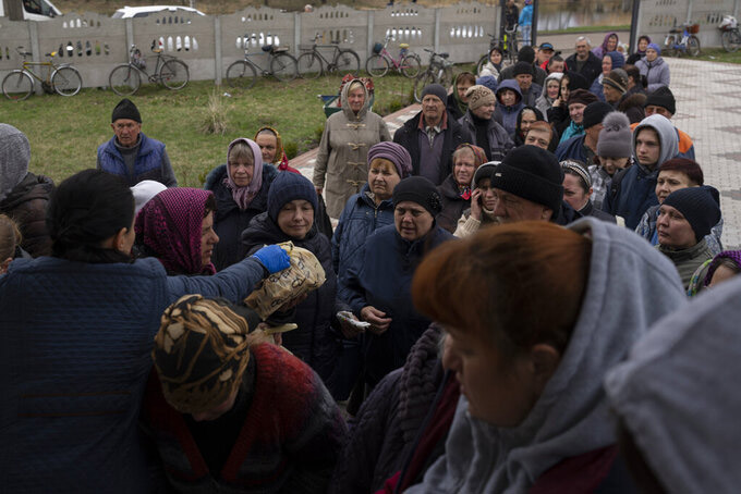 People receive food from a church in the town of Borodyanka, about 40 miles northwest of Kyiv, Ukraine, on Sunday, April 10, 2022. Several apartment buildings were destroyed during fighting between the Russian troops and the Ukrainian forces and the town is without electricity, water and heating. (AP Photo/Petros Giannakouri